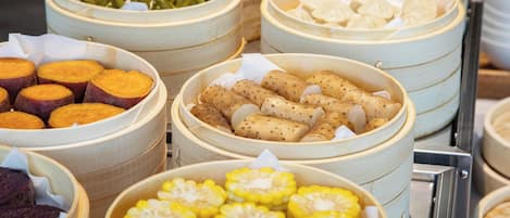 Un bufé con diversos alimentos presentados en recipientes de garmet.