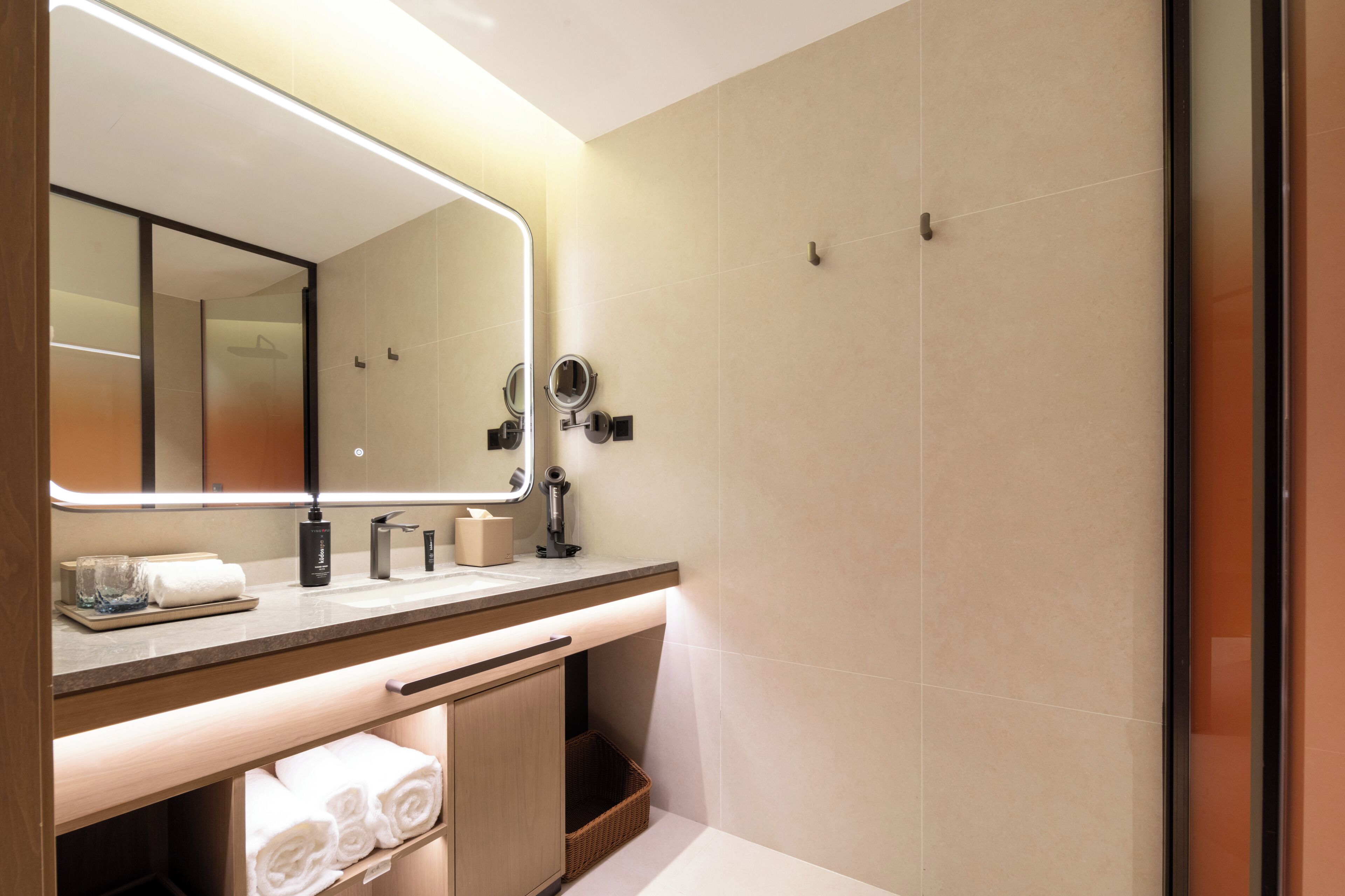 Une salle de bain moderne avec un grand miroir, un meuble-lavabo et un porte-serviettes.