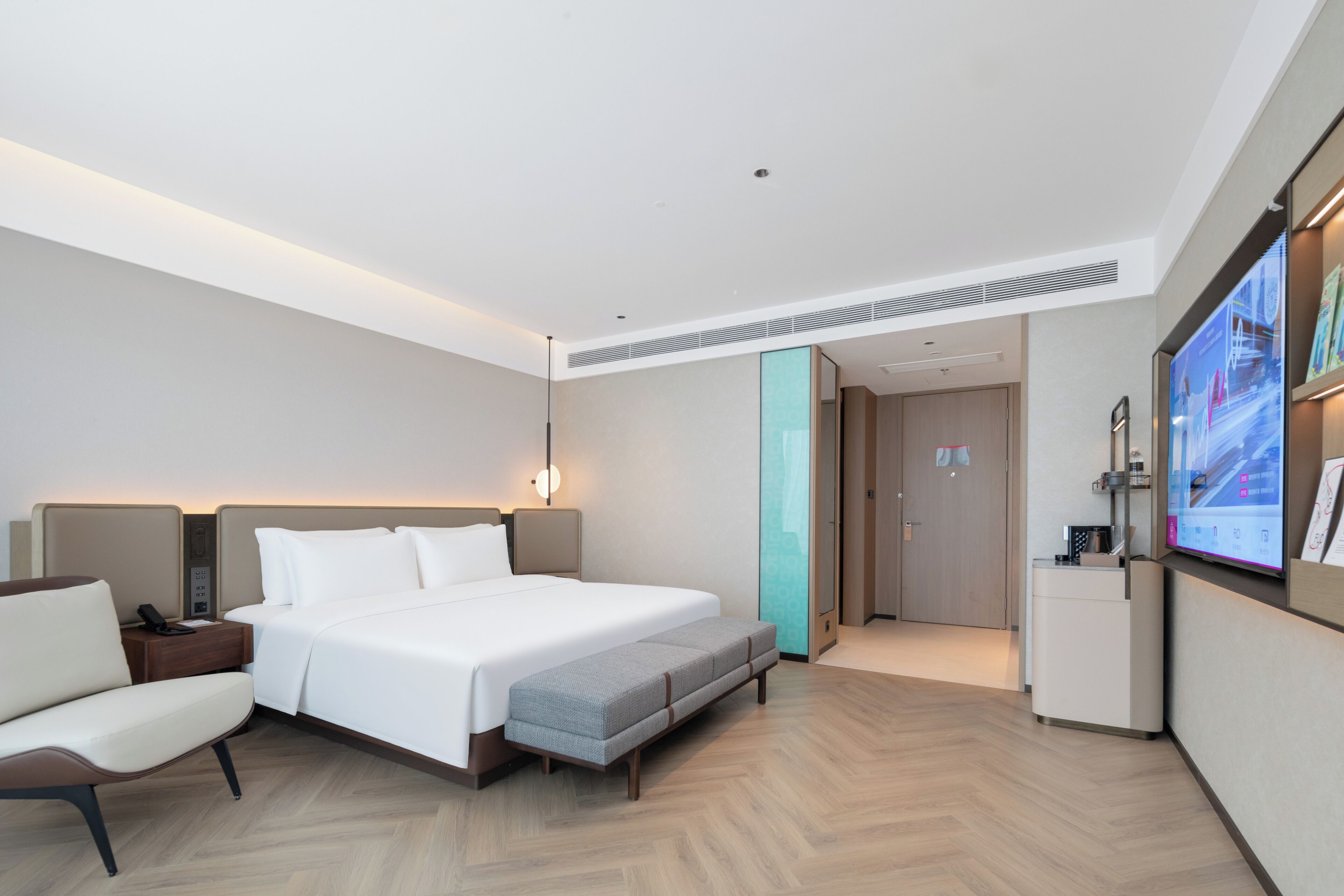 Une chambre d’hôtel moderne, dotée d’un grand lit, de tables de chevet, d’un bureau, d’une chaise, d’une télévision et d’une salle de bain.