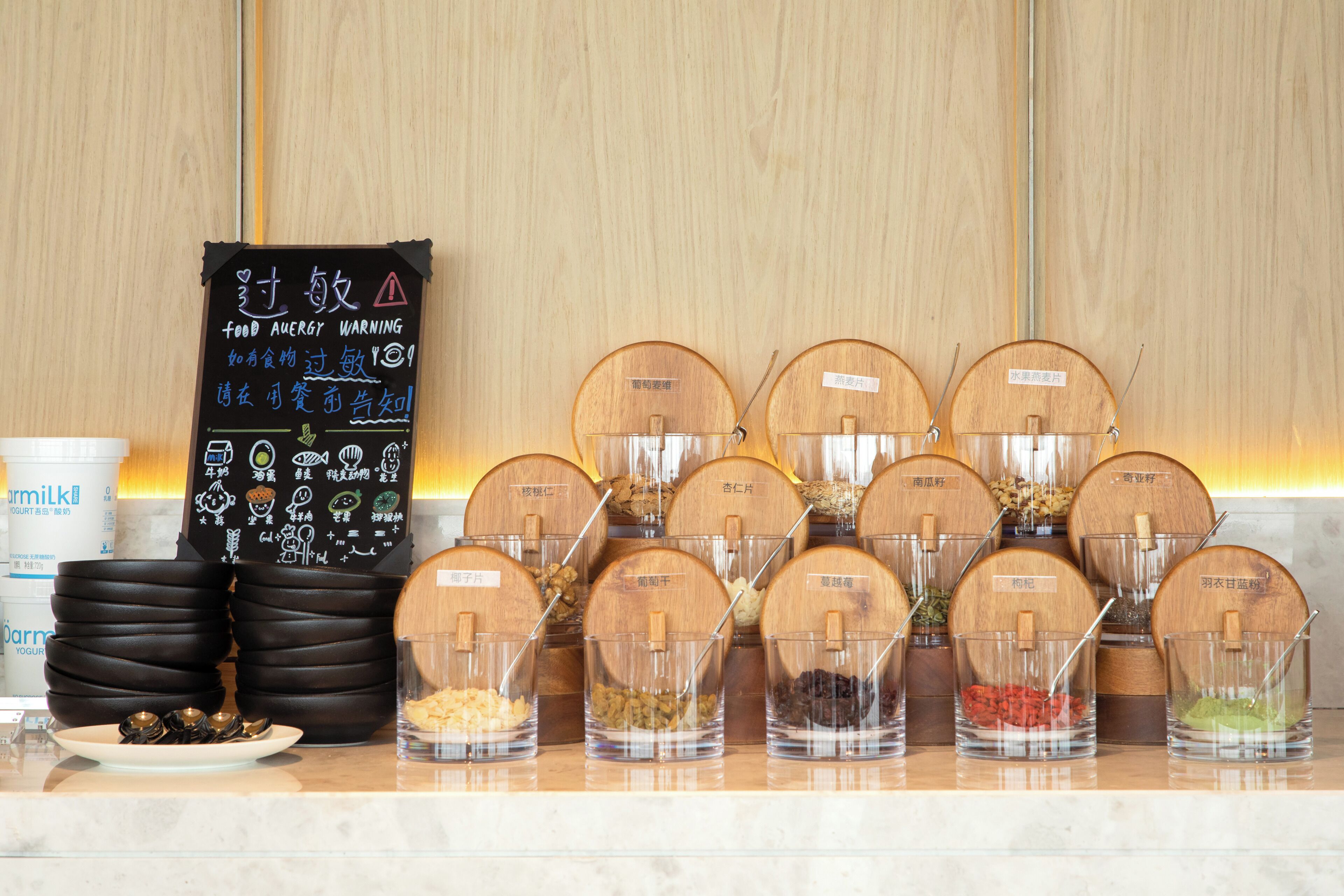 A food display with labeled containers of various ingredients and a chalkboard with food allergy warnings.