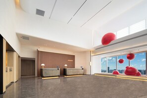 A modern hotel lobby with a reception desk, a city view through large windows, and a high ceiling. - Ying'n Flo by Langham, Wuhan, Hankou ICC (Wuhan)