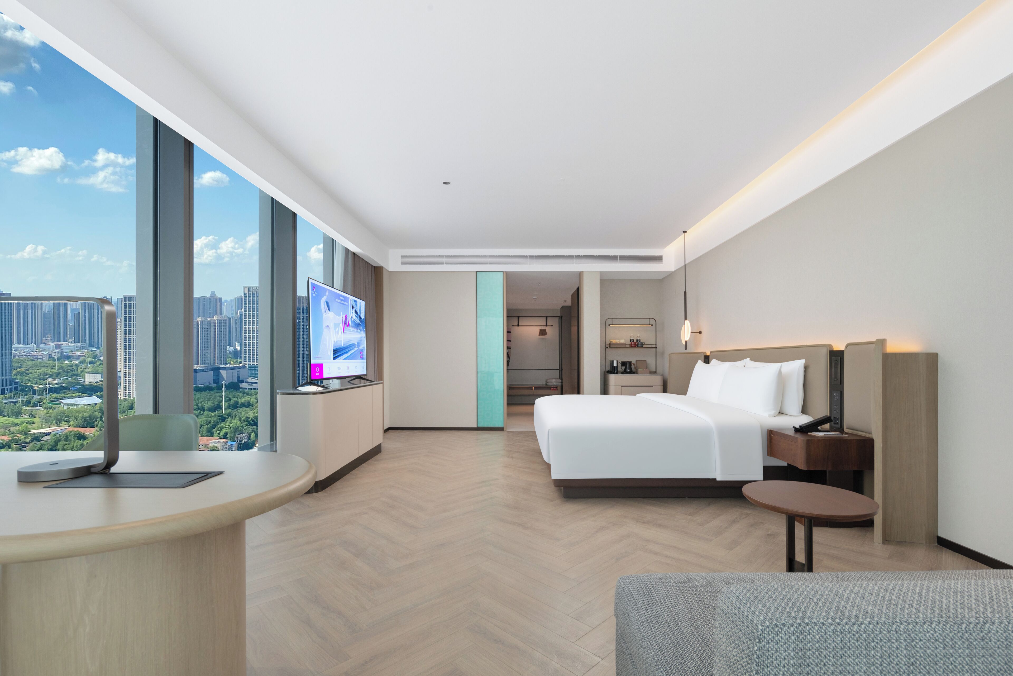 A modern hotel room with a large bed, a desk, and a television.