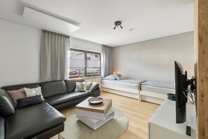 Ein modernes Wohnzimmer mit einer Couch, einem Couchtisch, einem Bett und einem Fernseher.