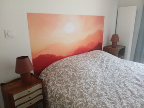 Ein Schlafzimmer mit einem Bett, einem Nachttisch, einer Lampe und einem an der Wand montierten Lichtschalter.