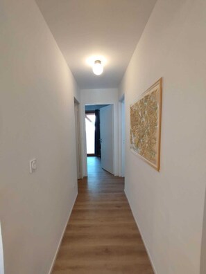 Ein Korridor mit Holzboden, weißen Wänden und einer Deckenleuchte.
