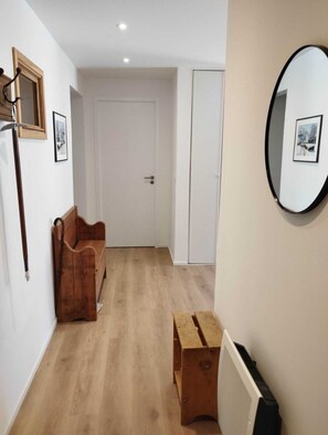 A hallway with a wooden bench, a radiator, and a door. - Spacious apartment with a south-facing garden and terraces (Le Monêtier-les-Bains)