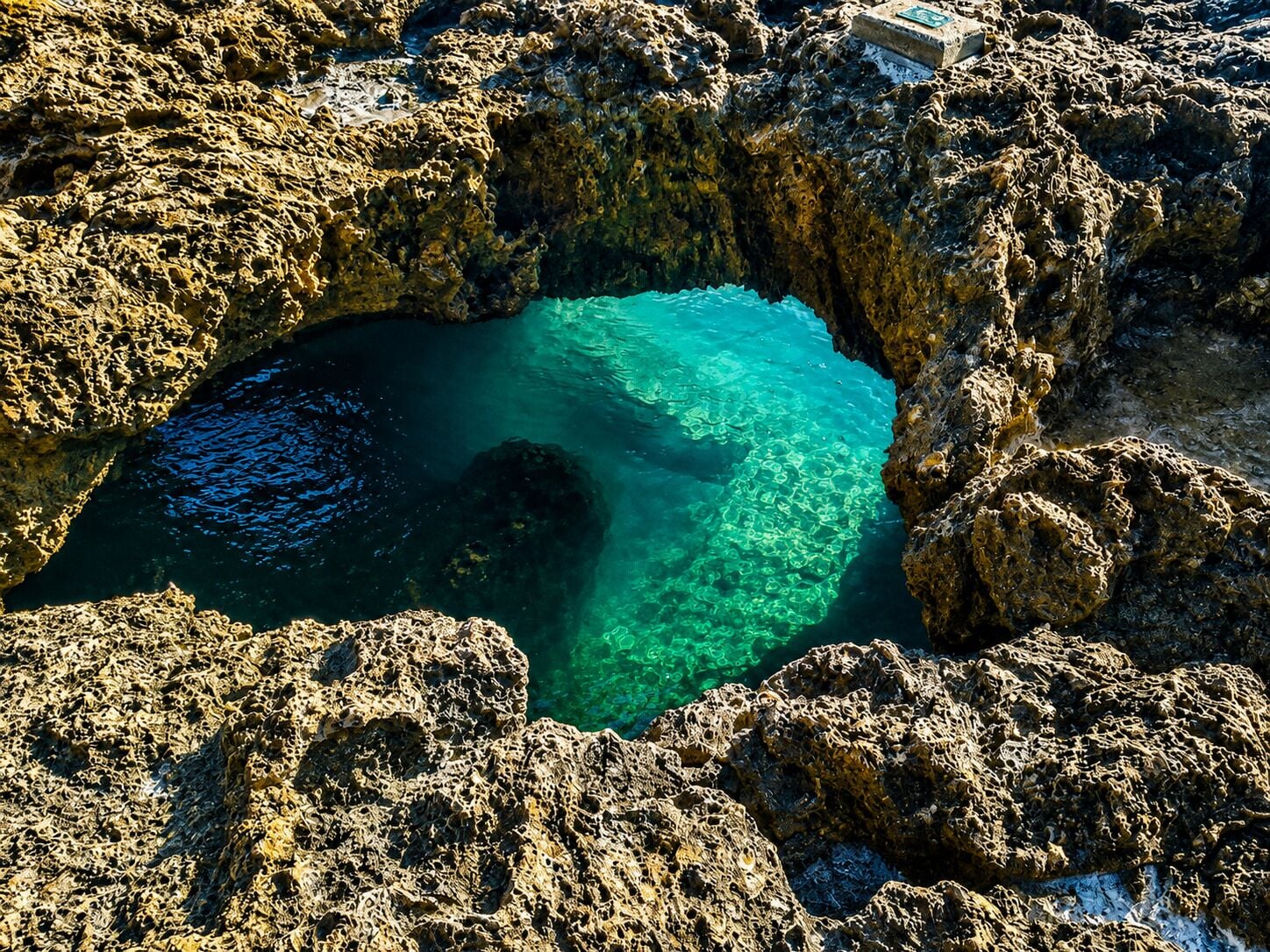 Een rotsachtig kustlandschap met een helderblauw waterlichaam, omringd door ruig terrein.