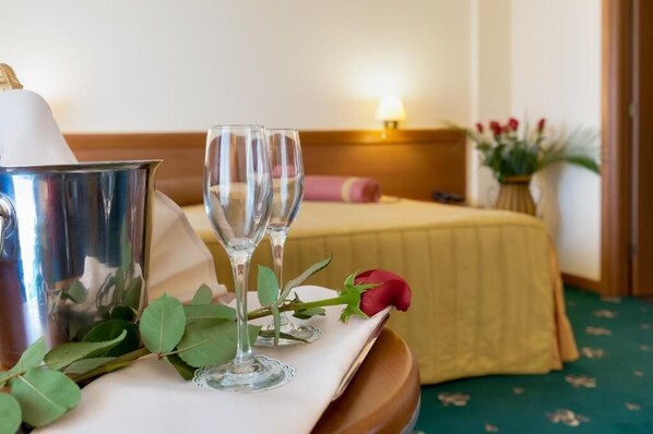A neatly arranged hotel room with a bed, a bedside table with a lamp, and a bouquet of flowers. - Hotel Palas (Constanța)