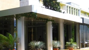 A hotel entrance with a covered porch, potted plants, and a clear view of the building's facade. - Hotel Palas (Constanța)