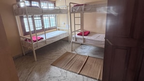 A room with bunk beds, a ceiling fan, and a window with bars.