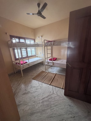 Habitación con literas, ventilador de techo y ventana con rejas.