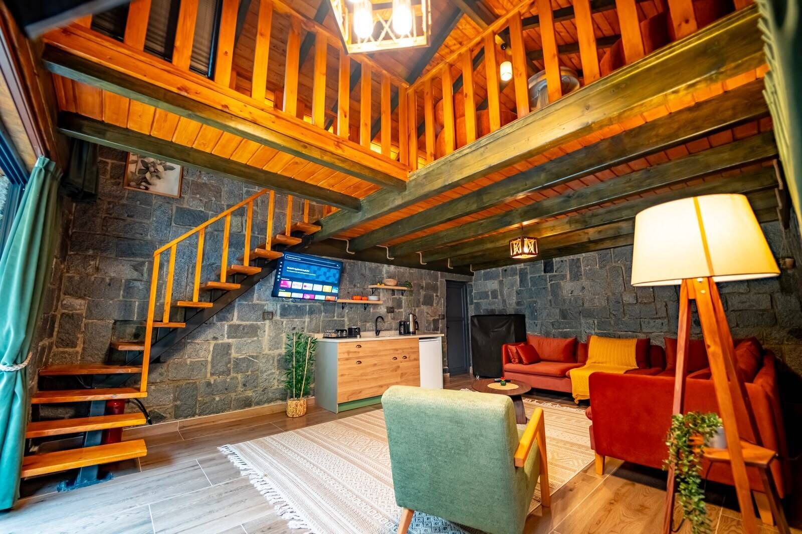 Un interior rústico con una pared de piedra, una escalera de madera, un sofá y una lámpara.