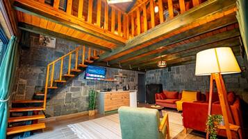 Un interior rústico con una pared de piedra, una escalera de madera, un sofá y una lámpara.