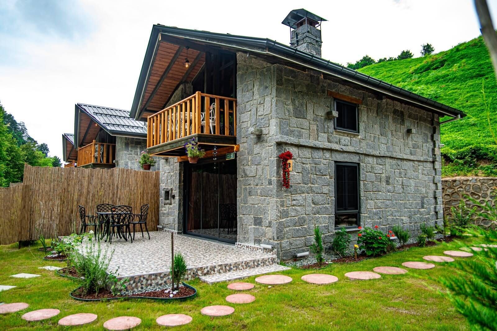 Ein Steinhaus mit einem Balkon, einer Holzterrasse und einem Steinweg, der zum Eingang führt.