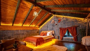Una habitación acogedora con una cama, una mesa de madera, una silla y una pared de piedra.