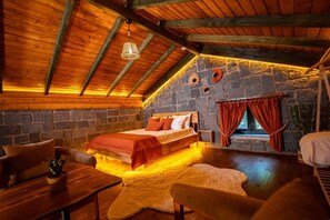 A cozy room with a bed, a wooden table, a chair, and a stone wall. - Dolana Wadi Taş Evleri (Ardeşen)