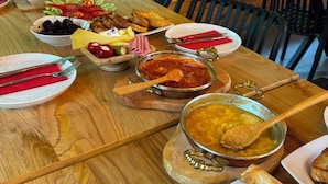 A wooden dining table with various dishes, including bread, cheese, and a bowl of soup. - Dolana Wadi Taş Evleri (Ardeşen)