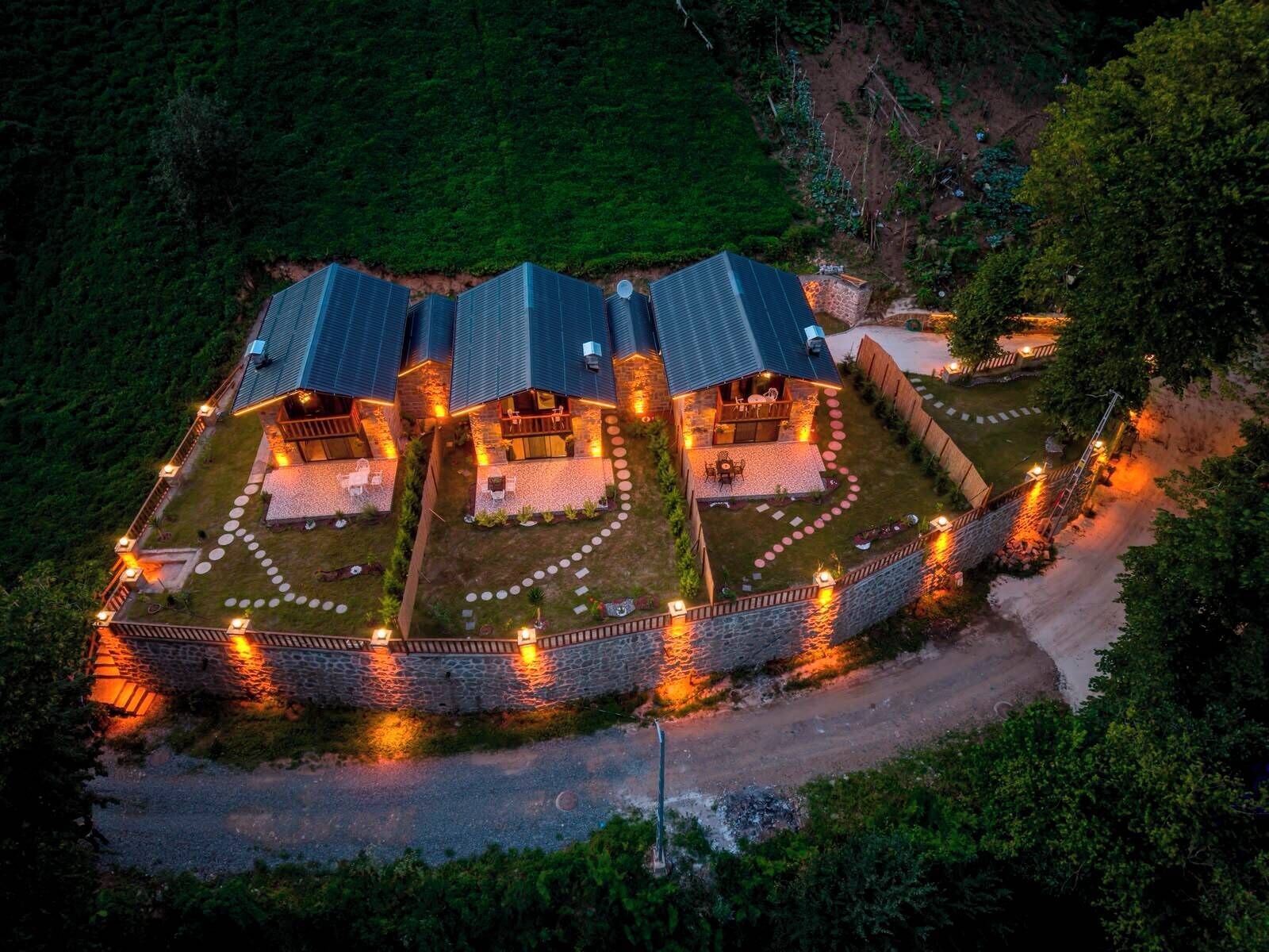 Un edificio de varios pisos con un perímetro de piedra, varios balcones y un área exterior bien iluminada con senderos.