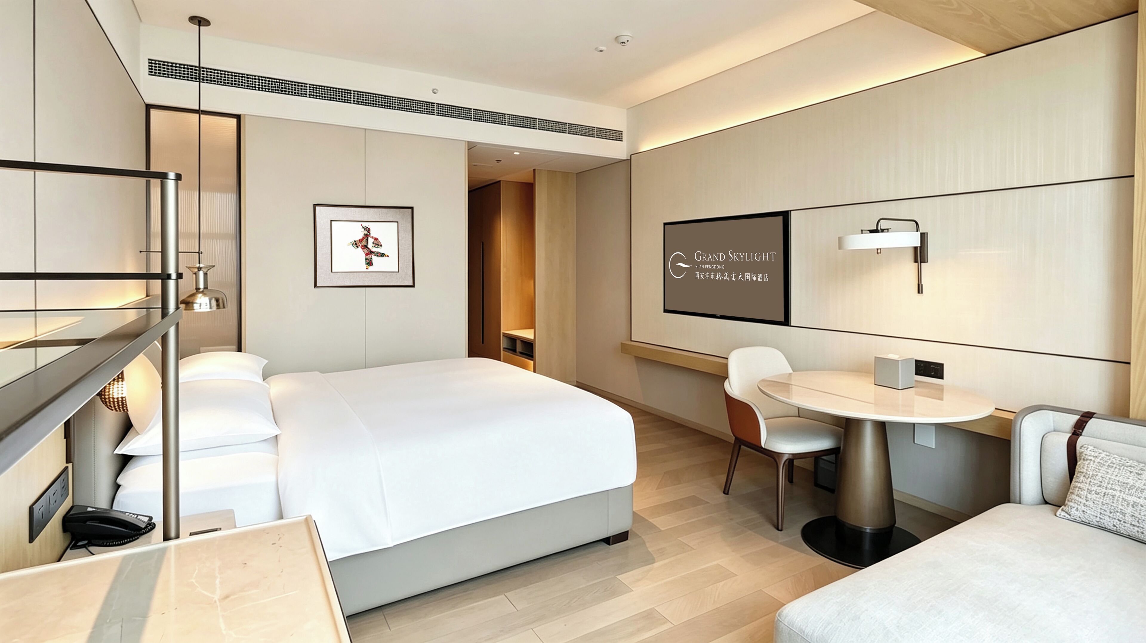 A modern hotel room with a large bed, a desk, a chair, and a small table. There is a framed picture on the wall and a sign with text.