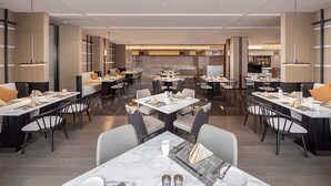 A modern restaurant with multiple dining tables and chairs, a bar area, and a view of the kitchen in the background. - Xian Fengdong Grand SkyLight Hotel (Xi'an)