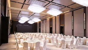 A banquet hall with round tables and chairs, large chandeliers, and a dark stage area. - Xian Fengdong Grand SkyLight Hotel (Xi'an)