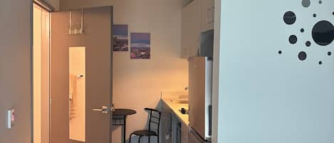 Un espacio habitable compacto con kitchenette, comedor y zona de estar.