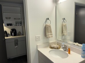 Ein Badezimmer mit einem weißen Waschbecken, einem Spiegel und einem Handtuchhalter.