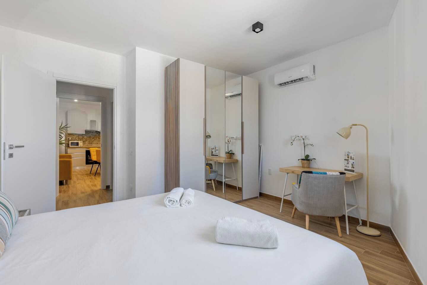 Une chambre d’hôtel avec un lit, un bureau, une chaise, une lampe et un miroir.