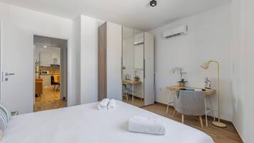 Une chambre d’hôtel avec un lit, un bureau, une chaise, une lampe et un miroir.