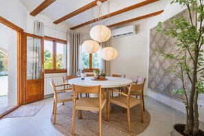 A dining area with a round table, wooden chairs, and a hanging light fixture. - Casa Hero - Javea, Costa Blanca (Javea)