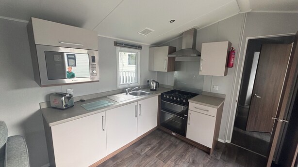 A compact kitchen with a microwave, stove, sink, and cabinets.