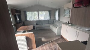 A compact living space with a kitchenette, a sofa, and a dining area. - Cosy seaside adventure home sweet home (Poole)