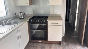A kitchen with a gas stove, oven, and a coffee maker. - Cosy seaside adventure home sweet home (Poole)