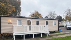 A mobile home with a front porch, a bench, and a small deck. - Cosy seaside adventure home sweet home (Poole)