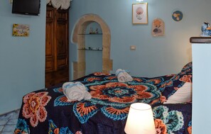 A bedroom with a bed, a wooden wardrobe, a stone archway, and a wall-mounted TV. - 1 bedroom beautiful home in Palazzolo Acreide (Palazzolo Acreide)