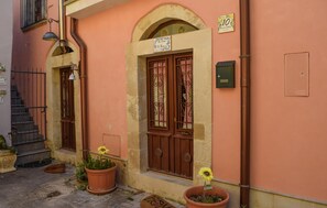 Ein Gebäude mit einem Schild, auf dem 'La Casa Di Sumo' steht, einer Tür mit schmiedeeisernem Zierdekor und einem kleinen Garten mit Pflanzen in Töpfen.