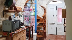 Una cocina con microondas, armarios y una escalera de madera que lleva a una puerta blanca.