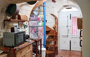 A kitchen with a microwave, cabinets, and a wooden staircase leading to a white door. - 1 bedroom beautiful home in Palazzolo Acreide (Palazzolo Acreide)