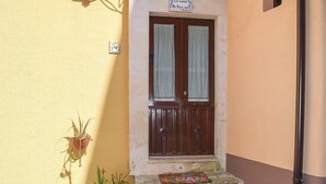 Una entrada de dos puertas con felpudo, plantas en macetas y un cartel sobre la puerta.