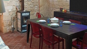 Un comedor con pared de piedra, chimenea y televisor.