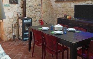 A dining area with a stone wall, a fireplace, and a television. - 1 bedroom beautiful home in Palazzolo Acreide (Palazzolo Acreide)