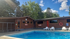 A wooden cabin with a pool, a no diving sign, and a lifebuoy.