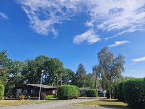 A lodge with a wooden exterior, a paved driveway, and a clear blue sky. - Cozy 3-Bed Chalet at Penlan Holiday Park | Pool (seasonal), WiFi & Dog Friendly (Cenarth)