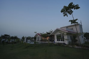 A modern two-story house with a swimming pool and a well-maintained lawn.