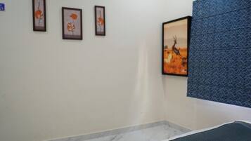 Une chambre d’hôtel avec un lit, un climatiseur fixé au mur et des œuvres d’art encadrées accrochées au mur.