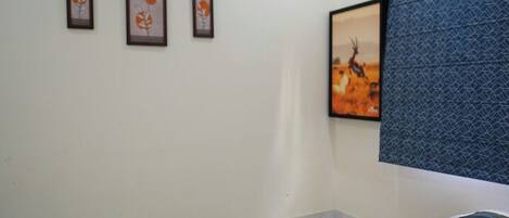 A hotel room with a bed, a wall-mounted air conditioner, and framed artwork on the wall.