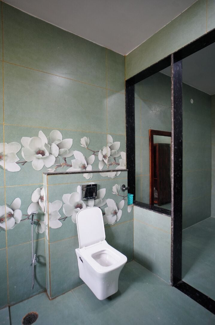 A bathroom with a toilet, a mirror, and a wall with a floral pattern.