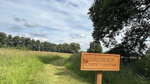 A wooden sign indicating 'Cabooze & Co. Cabin Parking' with a grassy path leading to a wooded area. - Literally do Nothing but Relax & Unwind (Worcester)
