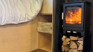 A cozy room with a bed, a wood-burning stove, and a patterned rug.