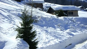 Schneebedeckte Landschaft mit einem einzelnen Baum und einem kleinen Gebäude.